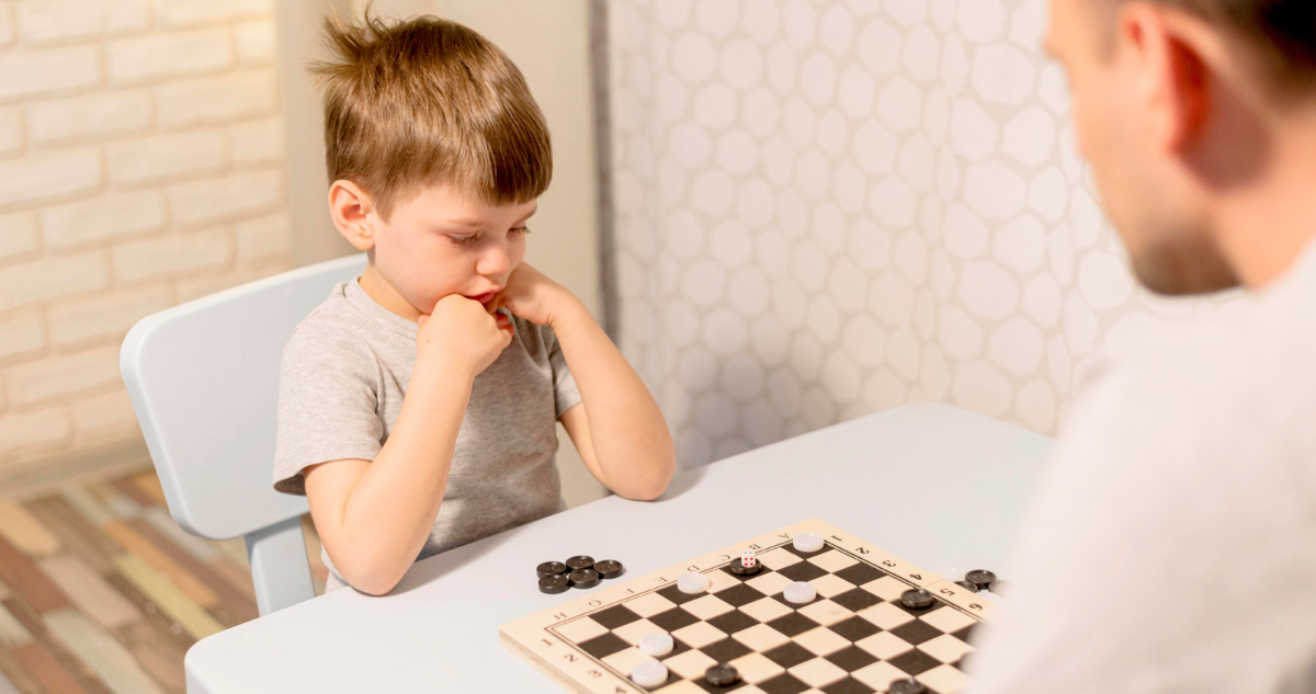 Niño jugando damas con su padre. Estudio descubrió que los niños tienen aprendizaje más rápido que los adultos
