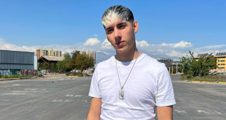 El cantante Pailita mira serio a la cámara en lo que parece ser un estacionamiento.