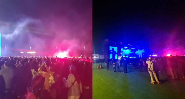 El público de Travis Scott presenciando el concierto mientras una bemgala está encendida en medio de la multitud.