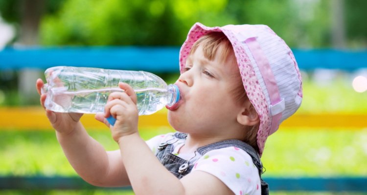 Bebé de dos años bebiendo agua en una botella. Señales y signos de deshidratación en bebés por la ola de calor
