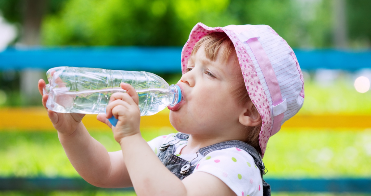 Bebé de dos años bebiendo agua en una botella. Señales y signos de deshidratación en bebés por la ola de calor