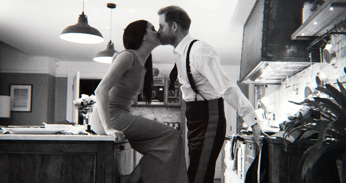 El principe Harry y su esposa Meghan Markle besandonse en una cocina, una de las fotografías ineditas que reveló su documental de Netflix