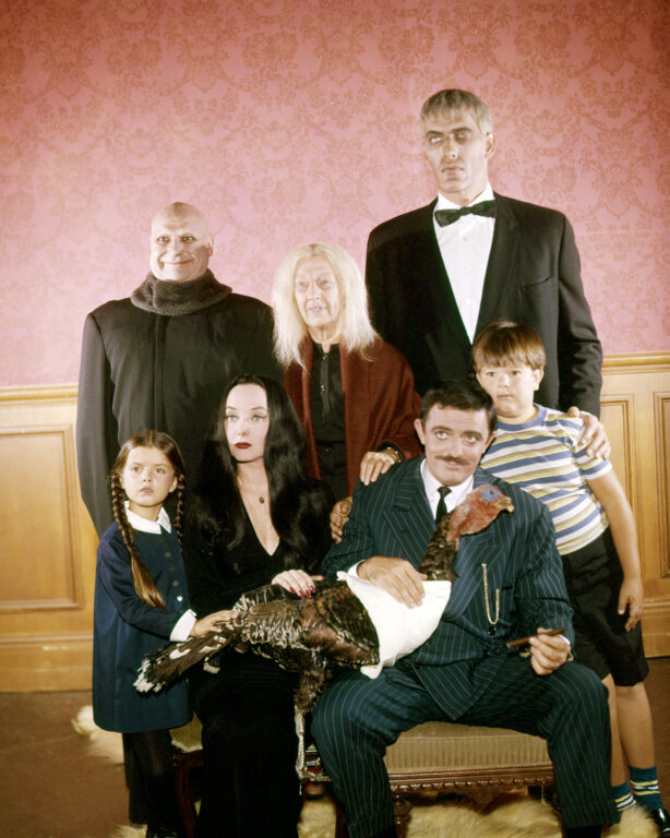 El reparto completo de Los Locos Addams posando para la cámara bajo sus respectivos personajes.