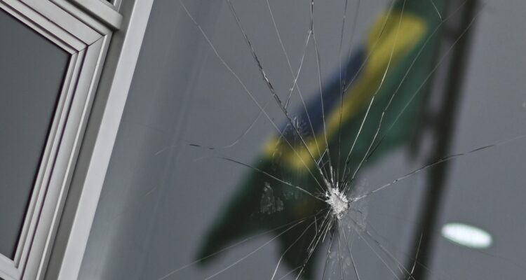 Fotografía que muestra la bandera de Brasil en el reflejo de los cristales rotos del Palacio del Planalto.