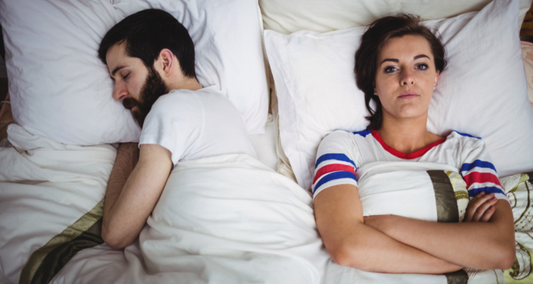 Pareja durmiendo mientras la mujer no puede conciliar el sueño. Chile sería el país que menos duerme de Latinoamérica