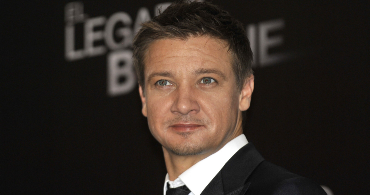 El actor Jeremy Renner mira hacia un costado con leve sonrisa.