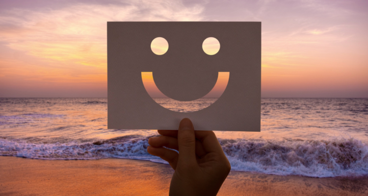 Persona sosteniendo stencil de cara feliz frente a un atardecer. 10 métodos para subir tu ánimo en 15 minutos (o menos) cuando no tienes ganas de nada