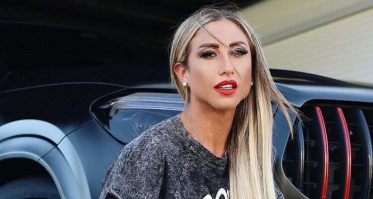La influencer Nicole Luli Moreno posa seria junto a un auto.