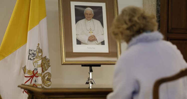 Una mujer firma en el libro de condolencias por el fallecimiento del Papa Benedicto XVI.