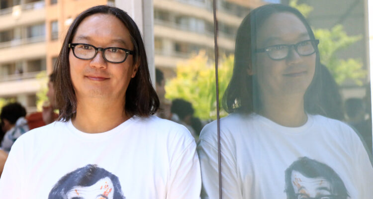 El productor Sergio Nakasone sonriendo para la cámara mientras se apoya en una ventana.