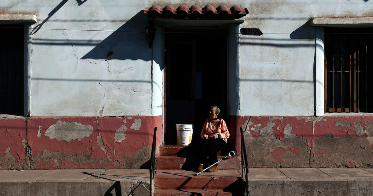 Adulta mayor sola en la puerta de su casa, en referencia a estudio que afirma que factores de riesgo de demencia producen sensación de soledad