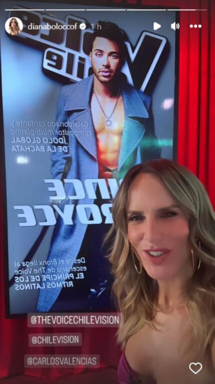 La animadora Diana Bolocco sonriendo con un poster de Prince Royce en el set de The Voice.