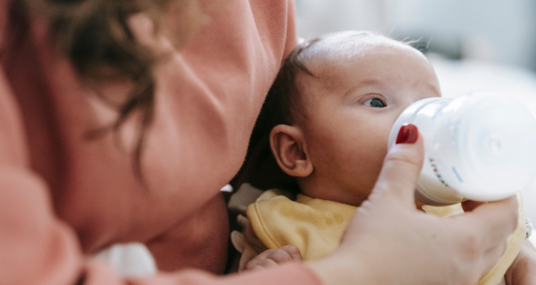 Bebé tomando leche de una mamadera en referencia a estudio que afirma que las fórmulas para bebés no tendrían respaldo científico