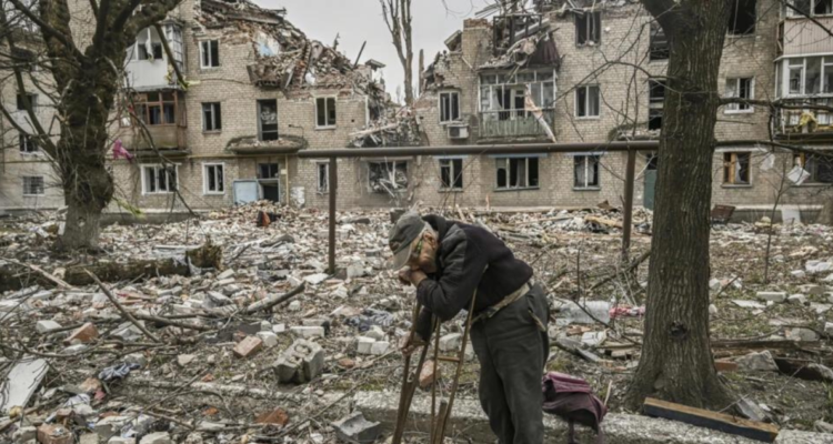 Un anciano recoge trozos de madera tras un bombardeo en Avdíivka