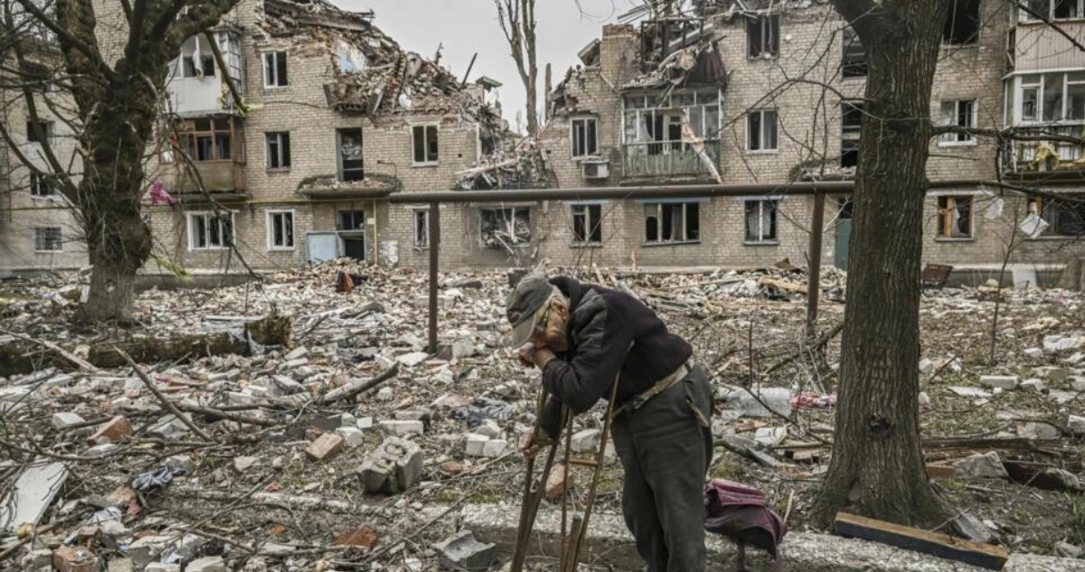 Un anciano recoge trozos de madera tras un bombardeo en Avdíivka