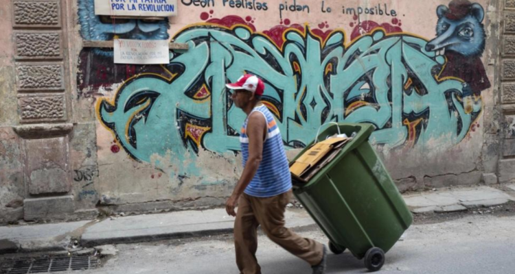Un hombre camina frente a carteles que llaman a los cubanos a votar en las elecciones legislativas