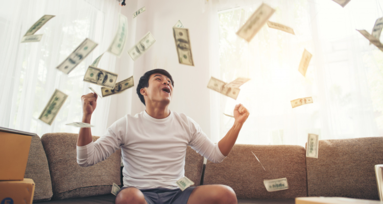 Hombre feliz con dinero en referencia a estudio que dice que a más ingresos mayor felicidad