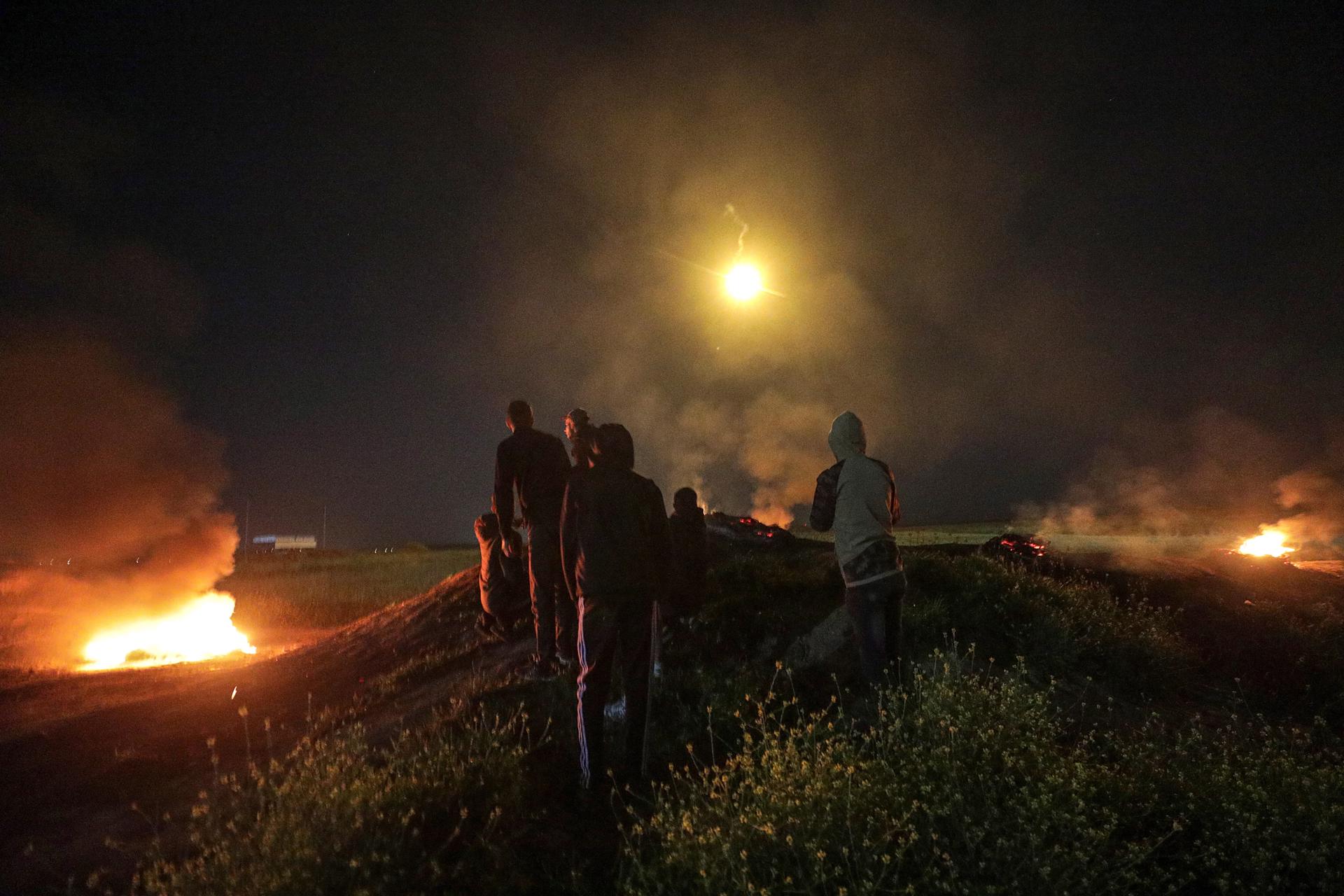 Palestinos observan un cohete disparado hacia Israel mientras se reúnen entre neumáticos en llamas cerca de la frontera en Gaza