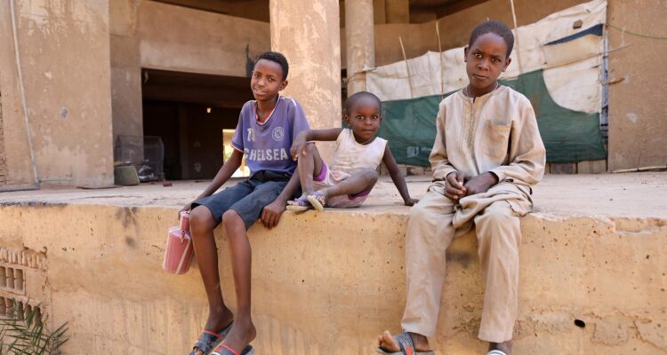 Niños sudaneses esperan en una calle mientras buscan agua potable en Jartum, Sudán