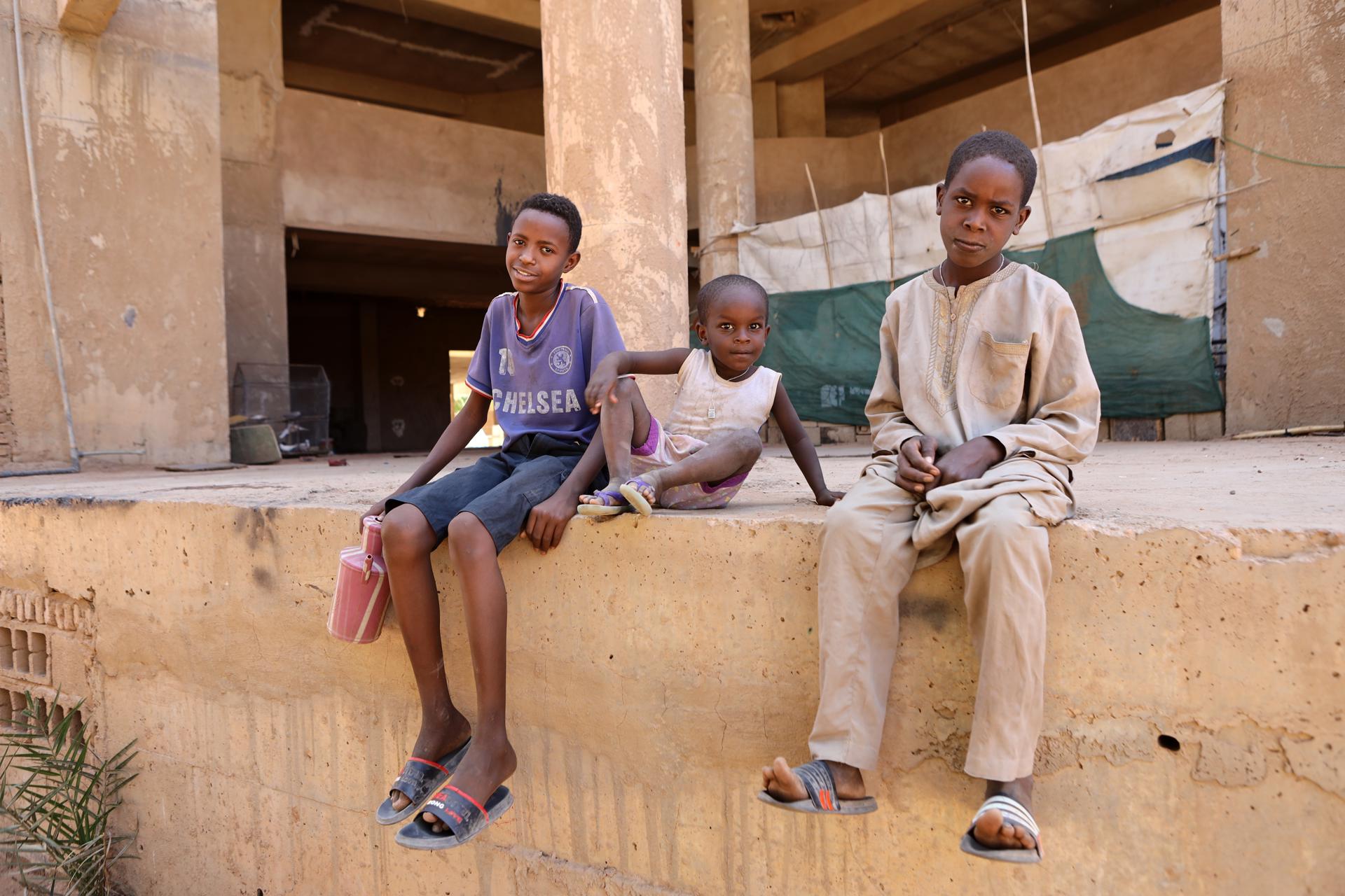Niños sudaneses esperan en una calle mientras buscan agua potable en Jartum, Sudán