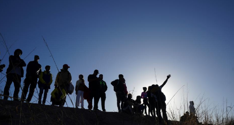 Un grupo de migrantes a contraluz miran hacia el horizonte