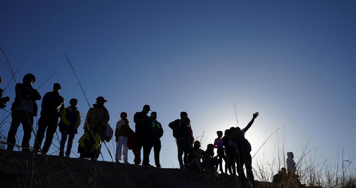 Un grupo de migrantes a contraluz miran hacia el horizonte