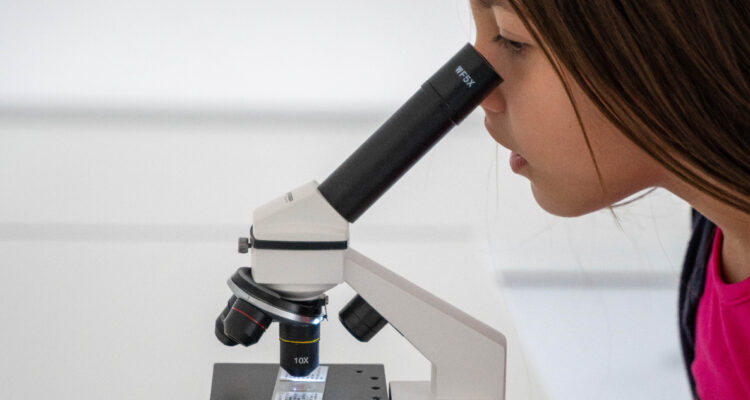 Niña mirando en un microscopio