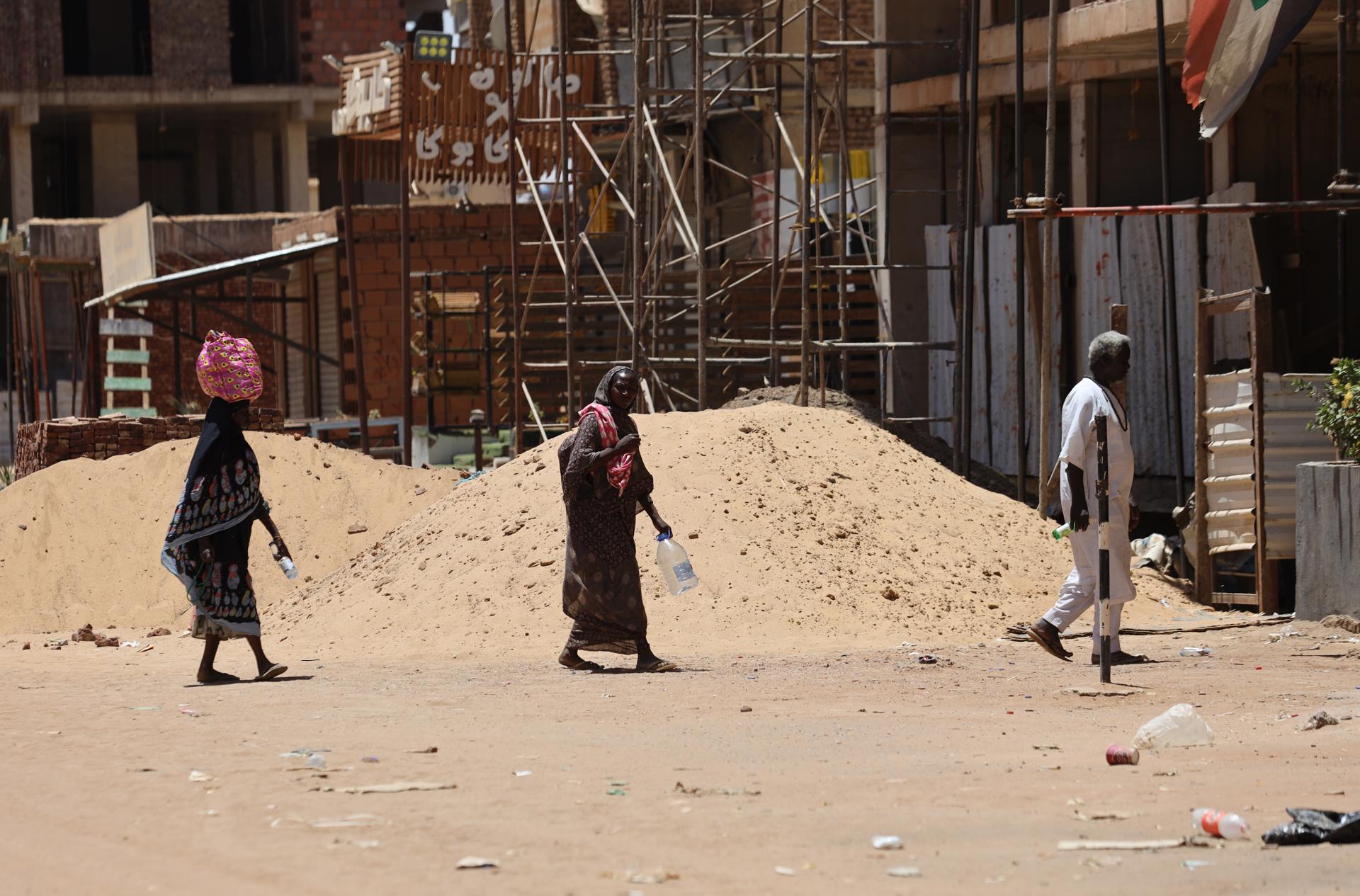 Sudaneses caminan con botellas vacías y bidones mientras buscan agua potable