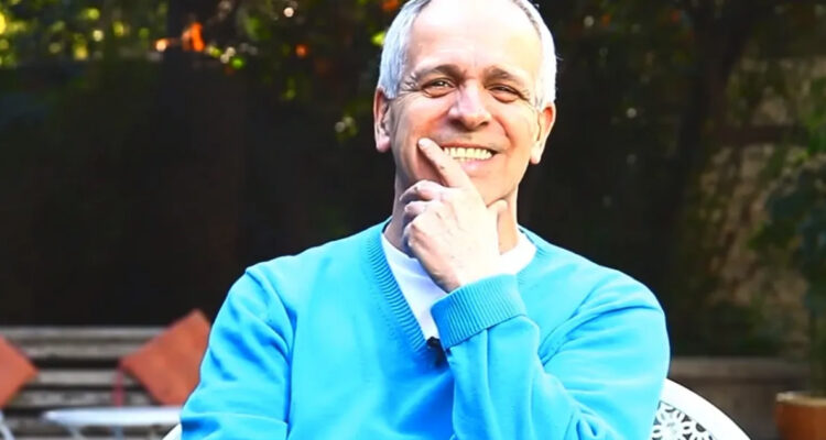 Augusto Góngora sonríe mientras se toma el rostro.