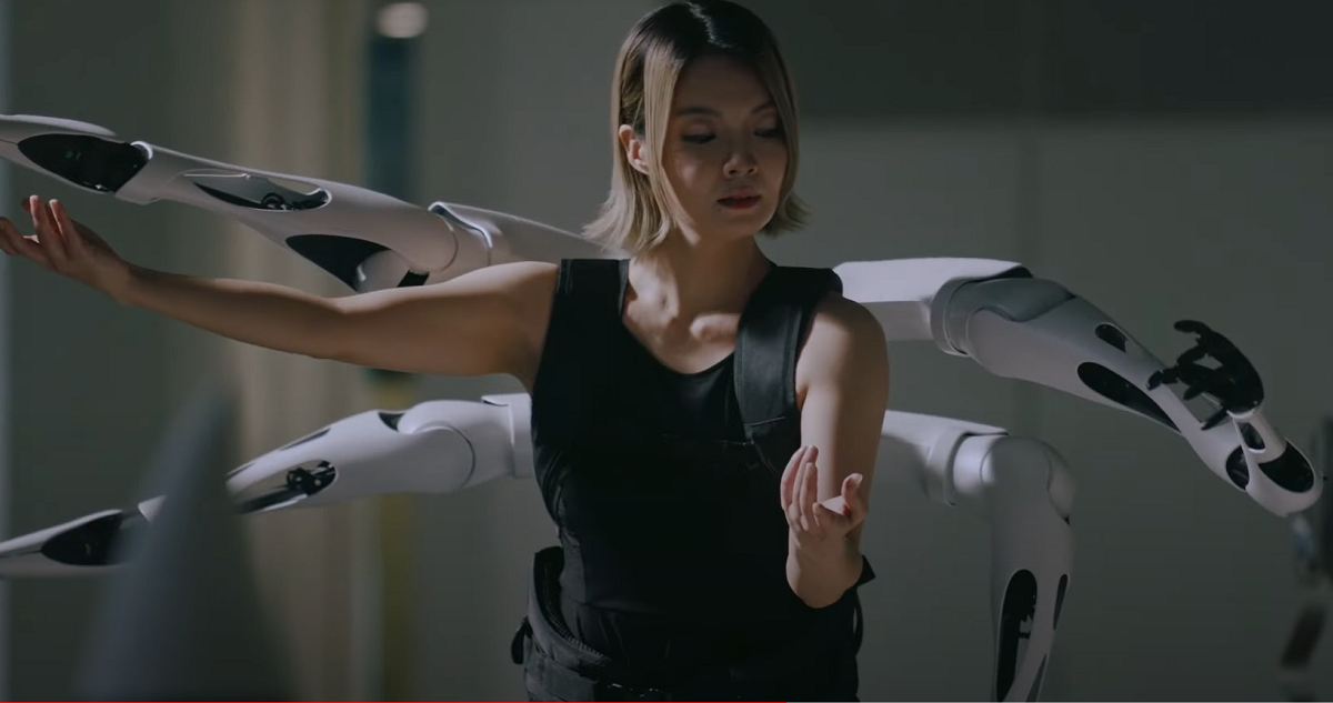 Una captura del video en que una modelo baila con los brazos robóticos.