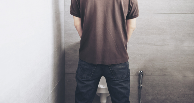 Hombre usando un urinario en referencia a la posición correcta de orinar