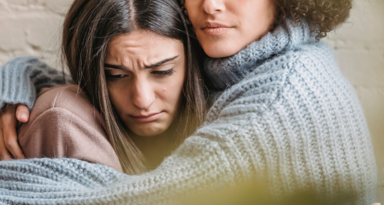 Mujer apesadumbrada siendo abrazada