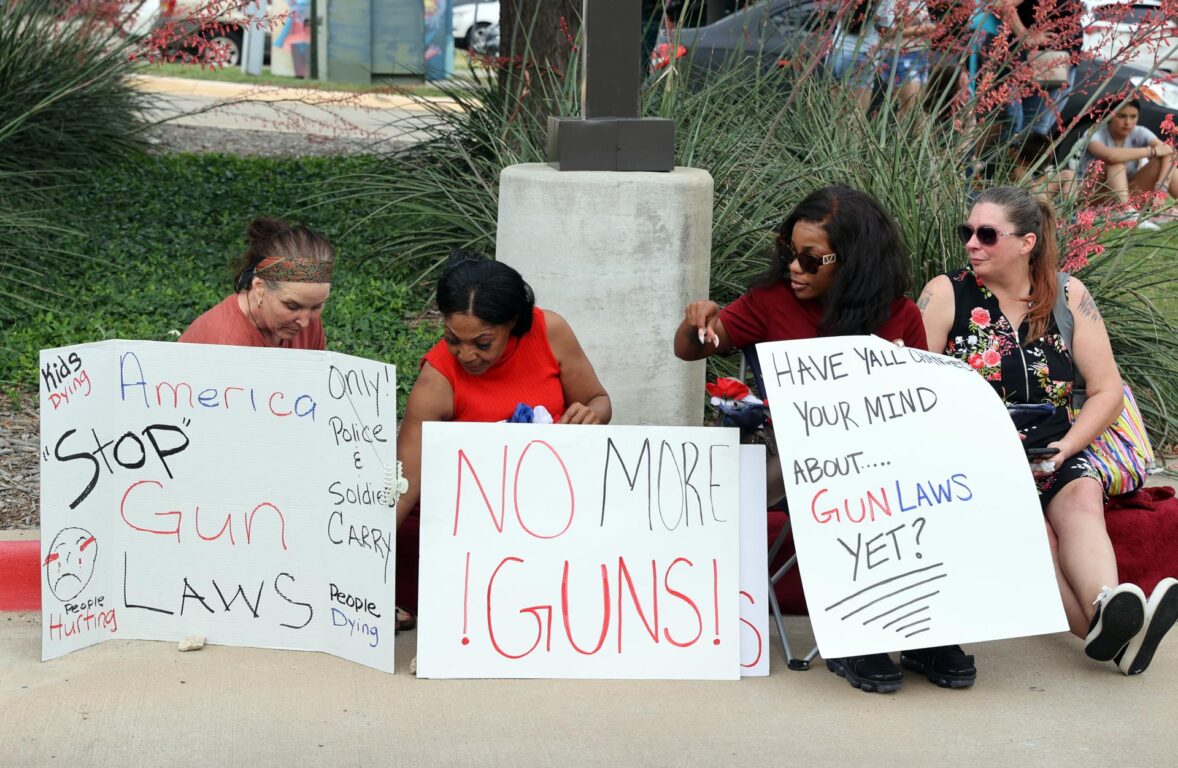 Mujeres con carteles sobre armas durante la vigilia por los fallecidos en el tiroteo