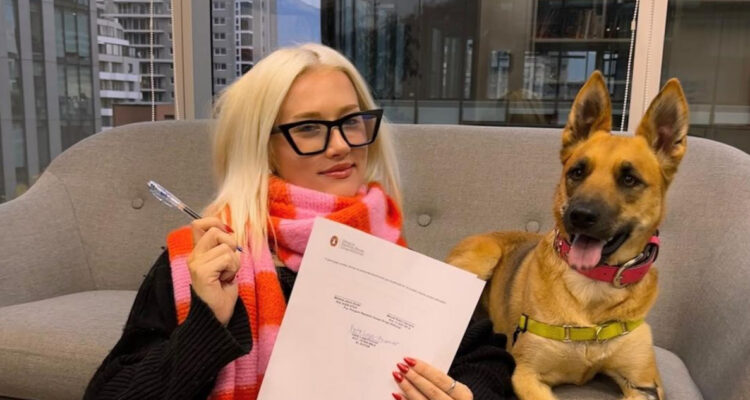 Vesta Lugg posa sonriente con el contrato para su próximo libro.