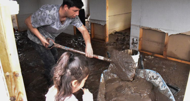 Hombre sacando barro de su casa por sistema frontal que dejó lluvias extremas en la cordillera de la zona central de Chile