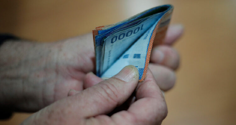 Persona sujetando un fajo de billetes de 10 mil y 20 mil