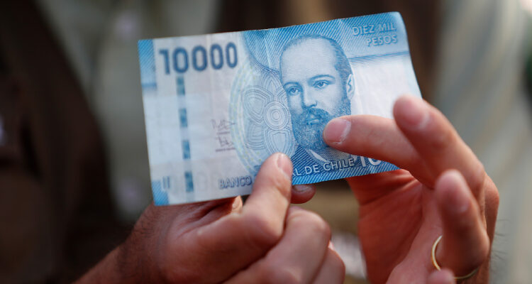 Hombre sosteniendo un billete de 10 mil pesos