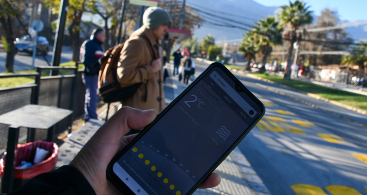 Persona sosteniendo celular a baja temperatura en referencia a la llegada del invierno en Chile