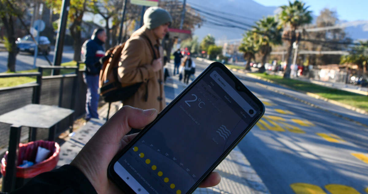 Persona sosteniendo celular a baja temperatura en referencia a la llegada del invierno en Chile