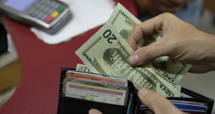 Persona venezolana pagando con dólares debido a la alta inflación persistente en el país