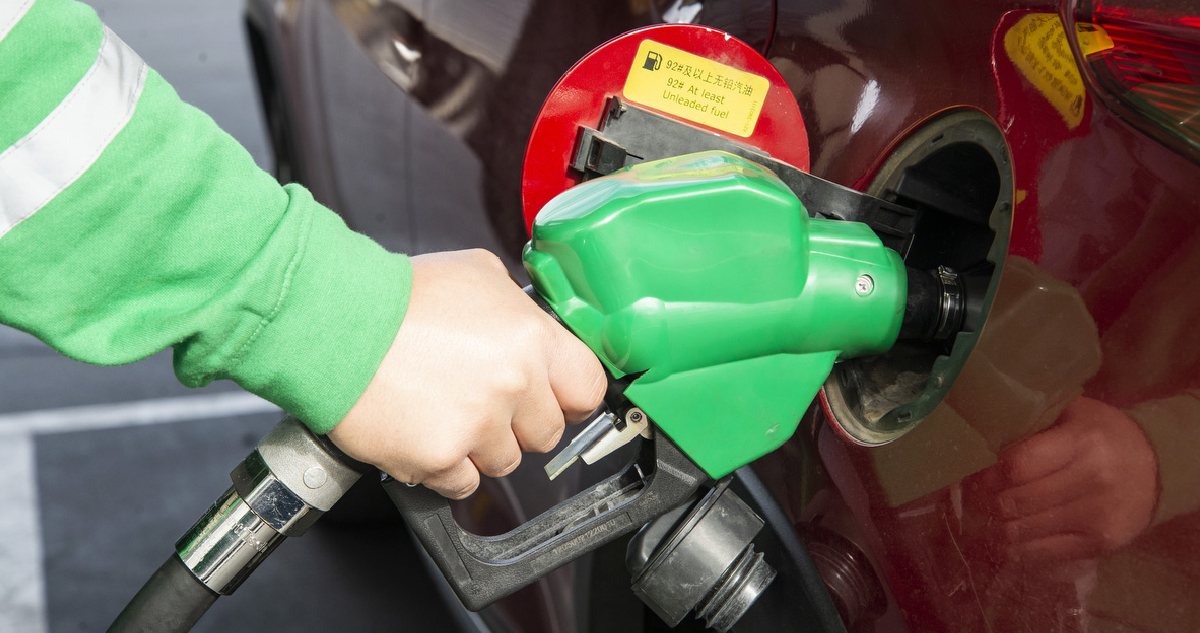 Hombre usando un vertedor de combustible en un auto rojo