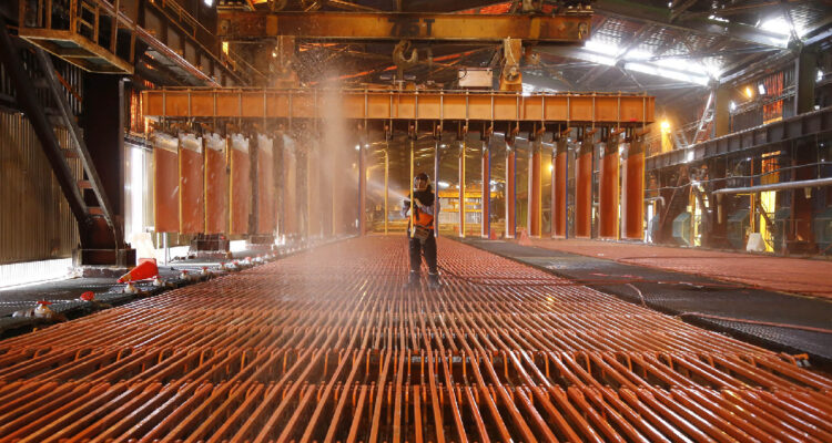 Hombre trabajando placas de cobre en una división de Antofagasta Minerals