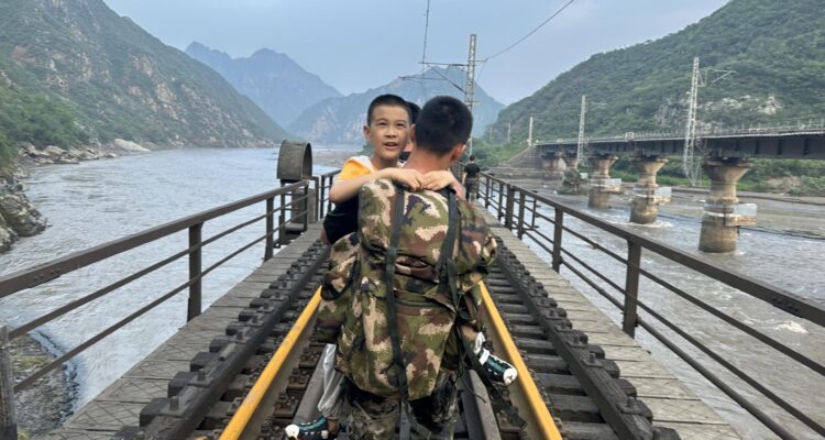 Un niño es llevado a un tren de transbordo en el distrito Mentougou de Beijing