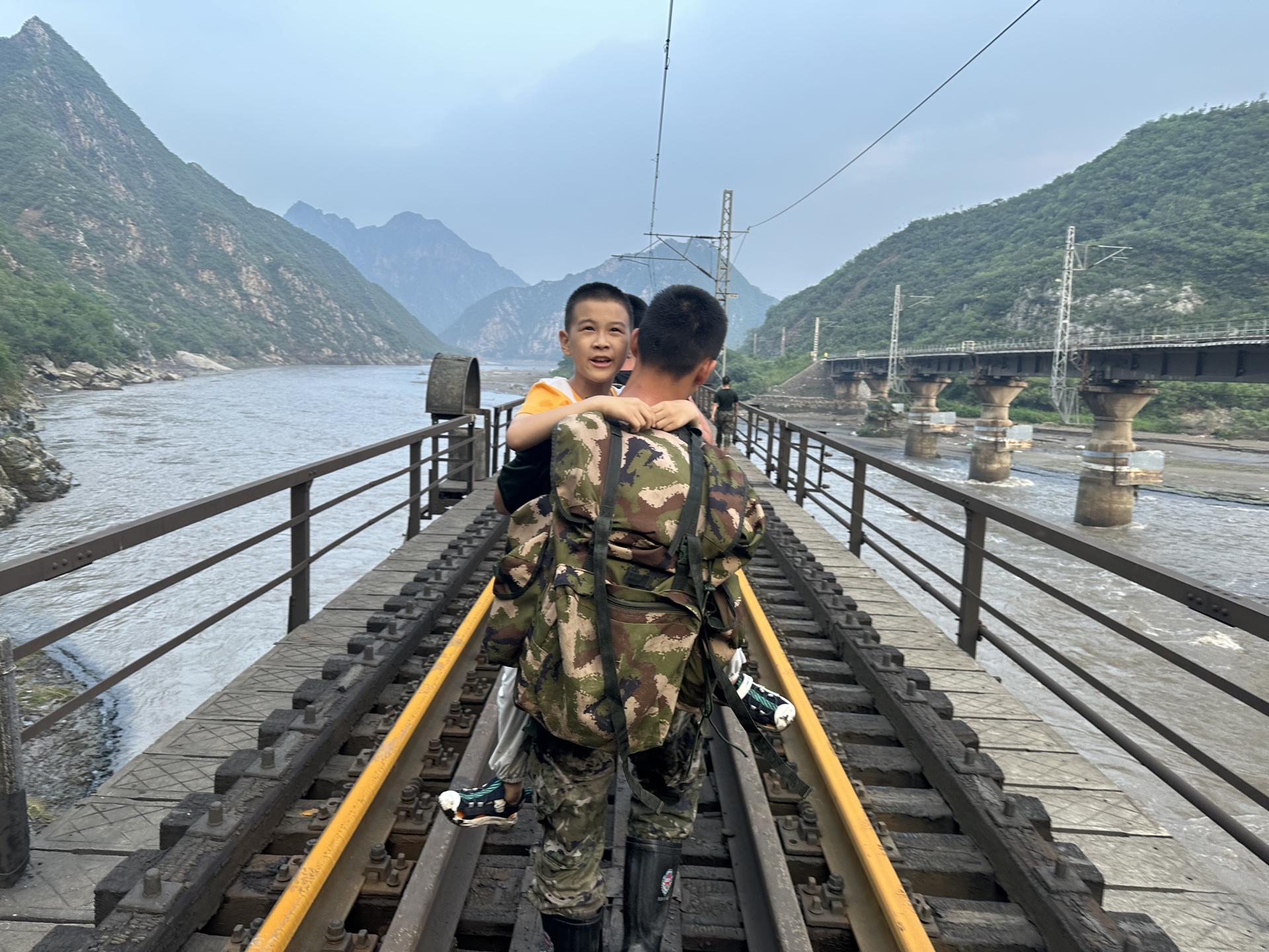 Un niño es llevado a un tren de transbordo en el distrito Mentougou de Beijing