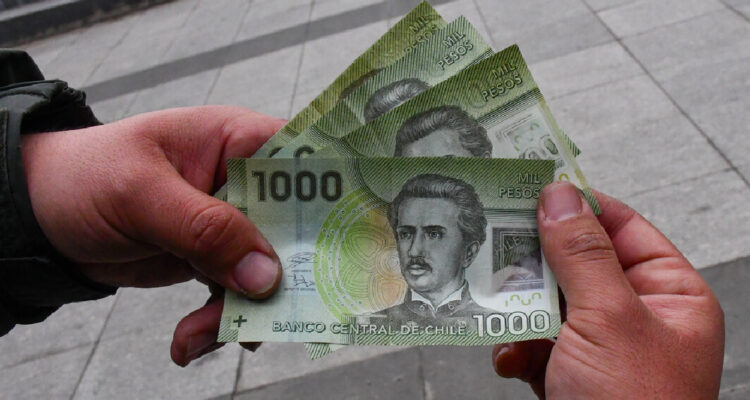 un hombre sosteniendo 3 billetes de mil pesos