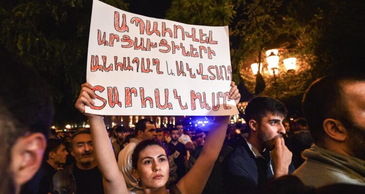 Una manifestante armenia sostiene un cartel durante una protesta el miércoles