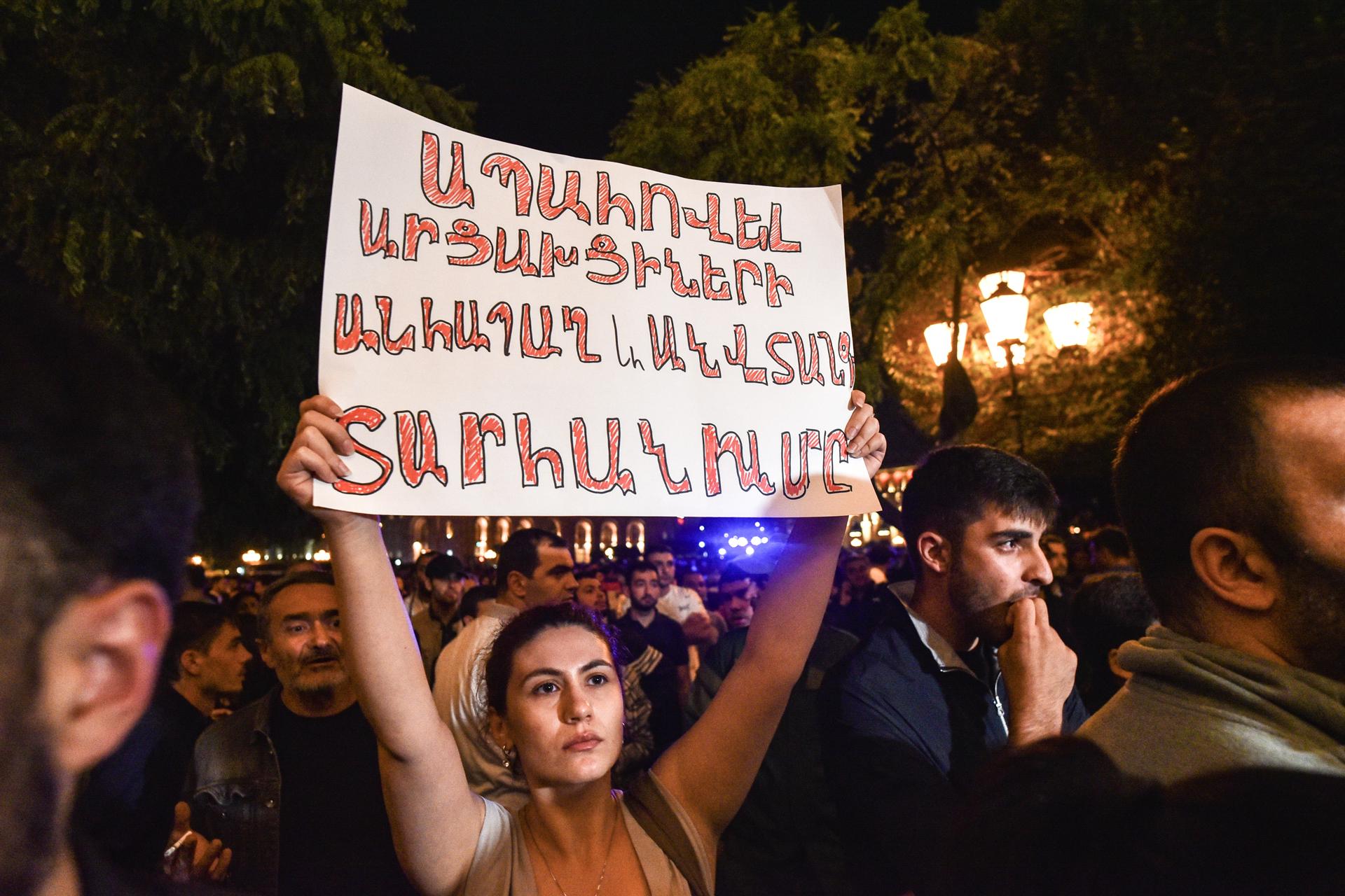 Una manifestante armenia sostiene un cartel durante una protesta el miércoles
