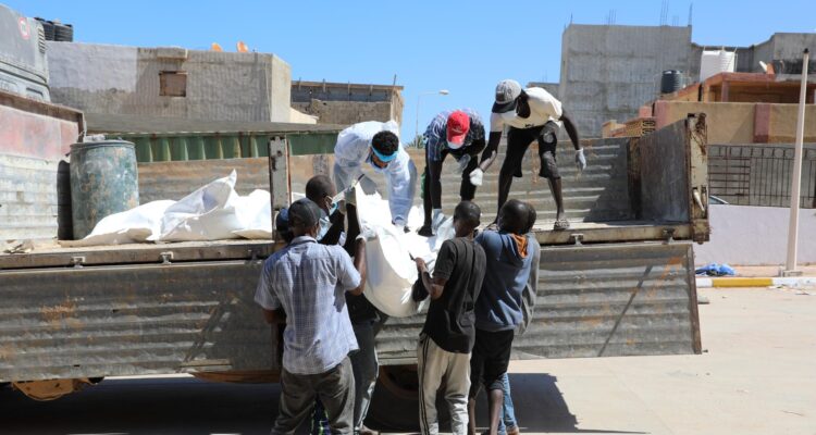 Socorristas transportan bolsas para cadáveres con los restos de víctimas arrastradas por el mar a la orilla