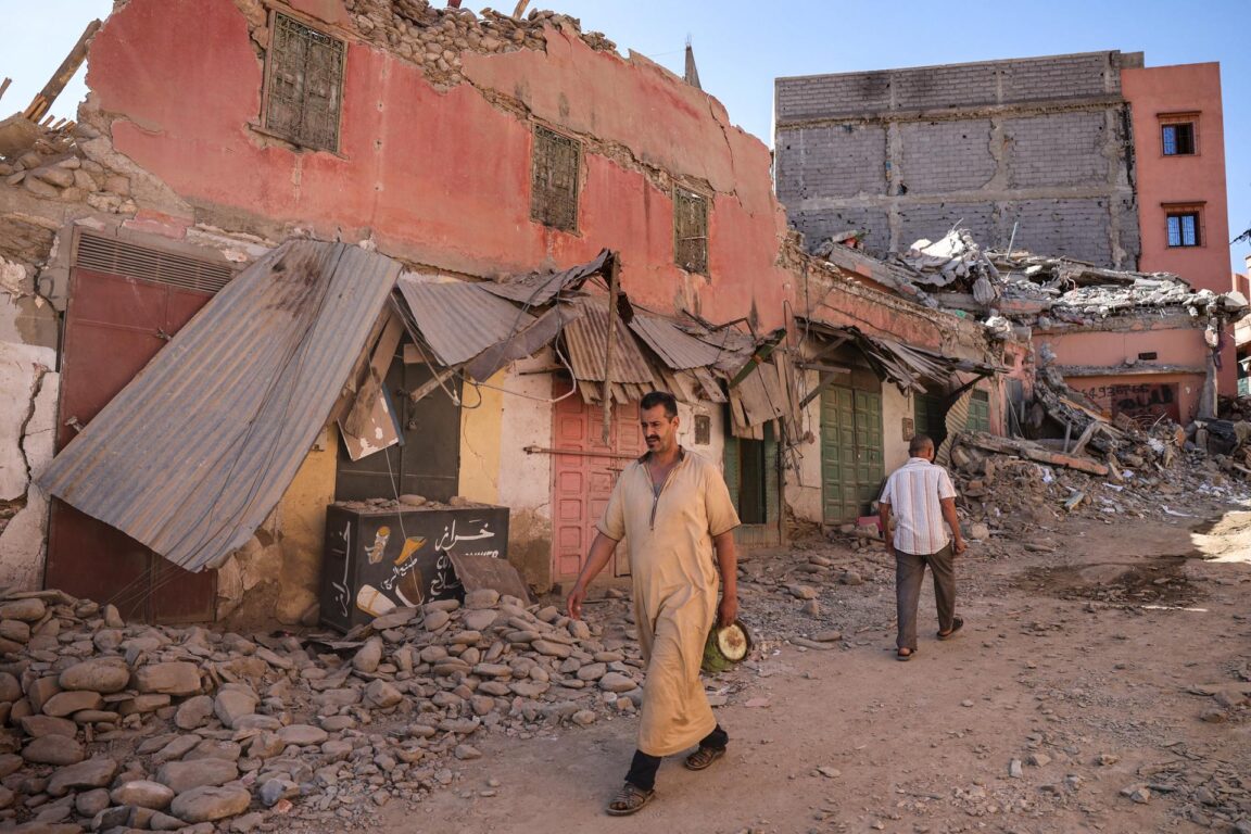 Gente caminando entre los escombros en la ciudad de Amizmiz
