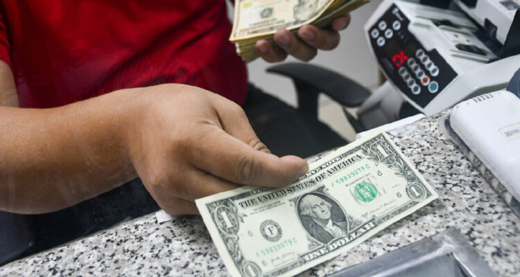 Mujer entregando dólares en una casa de cambio